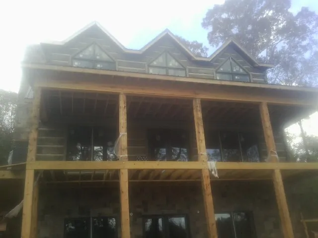 Dormers and porch framing on a large log home under construction — Roof Coating work by our crew in Tupelo